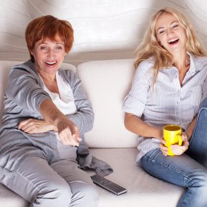 two women laughing watching tv